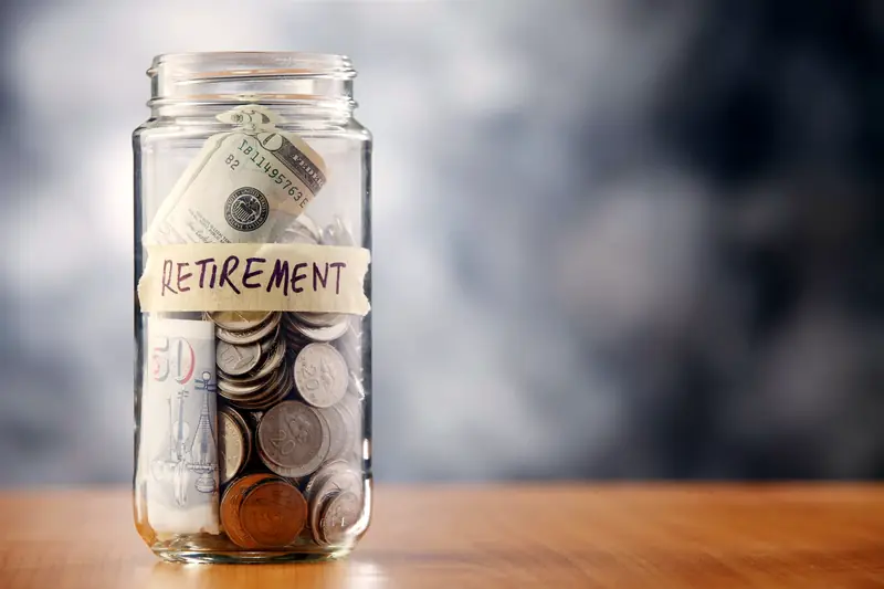 צנצנת חסכונות עם מטבעות ושטרות ותווית Retirement